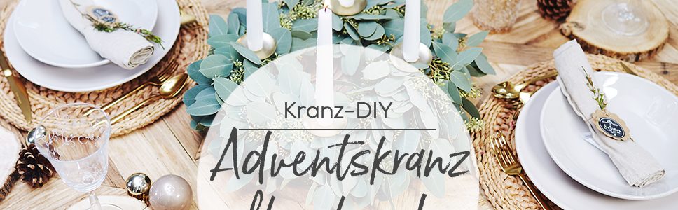 Moderner Eukalyptus Adventskranz auf einem Holztisch mit Gedecken für 4 Personen
