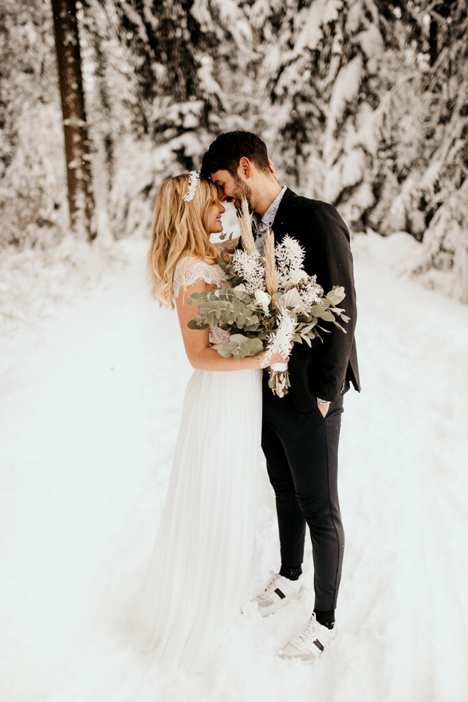 Braut und Bräutigam stehen im Schnee und schauen sich an